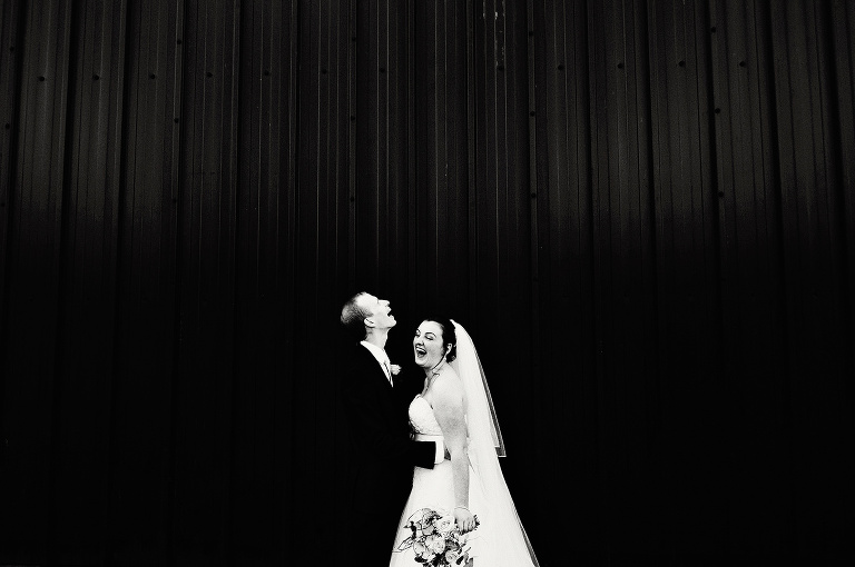 Black and white photo of brie and groom laughing at heaton house farm.