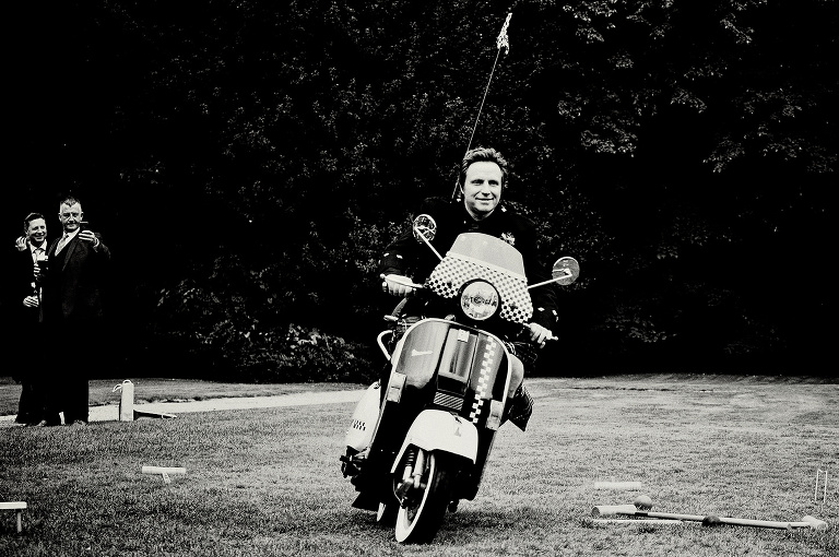 Groom riding a vespa at his wedding at Bartle Hall.