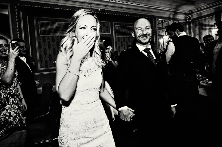 Black and white reportage wedding photo of a bride and groom walking into the goulburn suite at manchester hall.