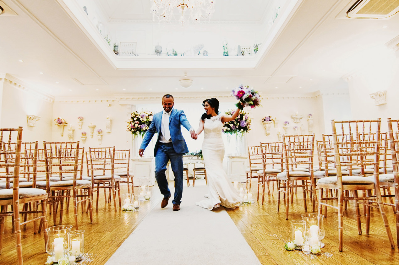Ashfield House Wedding Photography of a bride and groom celebrating walking down the aisle together with Rose Boutique flowers