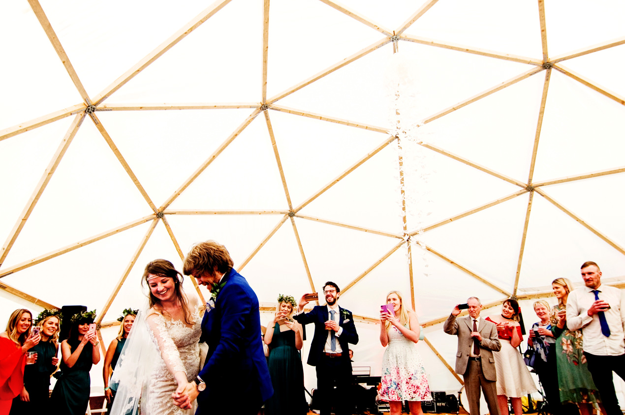 Wedding marquees, tents and domes are a great alternative to an indoor venue. Here is a bride and groom dancing inside their festival wedding dome supplied by Baya Hire.