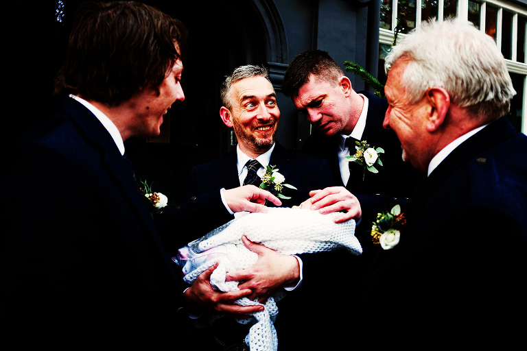 Groomsmen in kilts outside oddfellows in cheshter.s with a tiny baby.