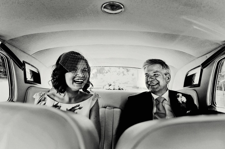 Bride with father laughing before ceremony at Samlesbury Hall.