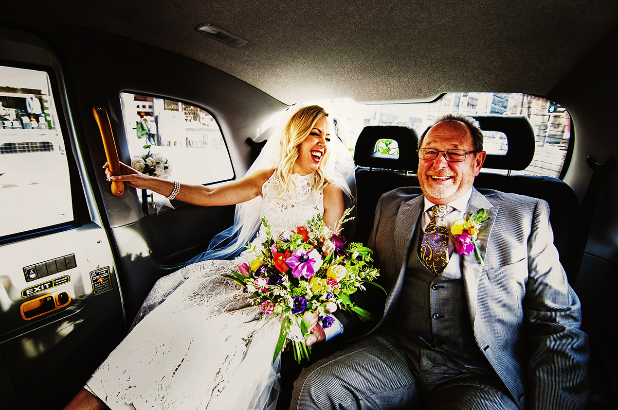 Bride and Dad travelling in a black cab through the city to her wedding at Manchester Hall.