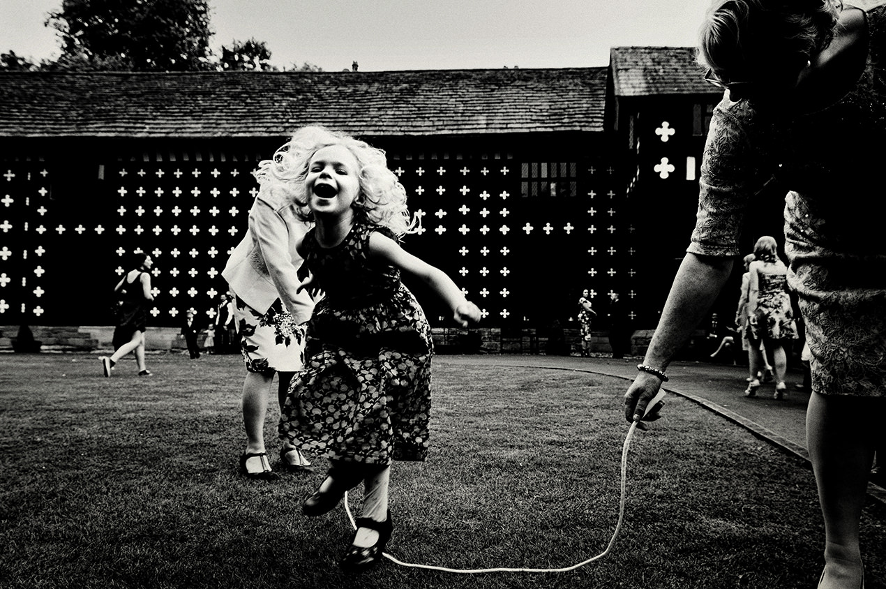 Black and white fun unposed photo of a young girl skipping at Samlesbury hall.