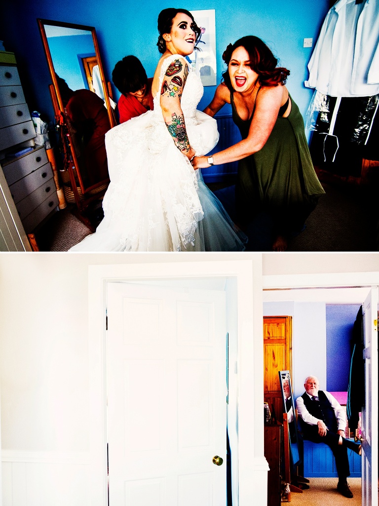 Tattooed bride putting her wedding dress on with sister and mum.